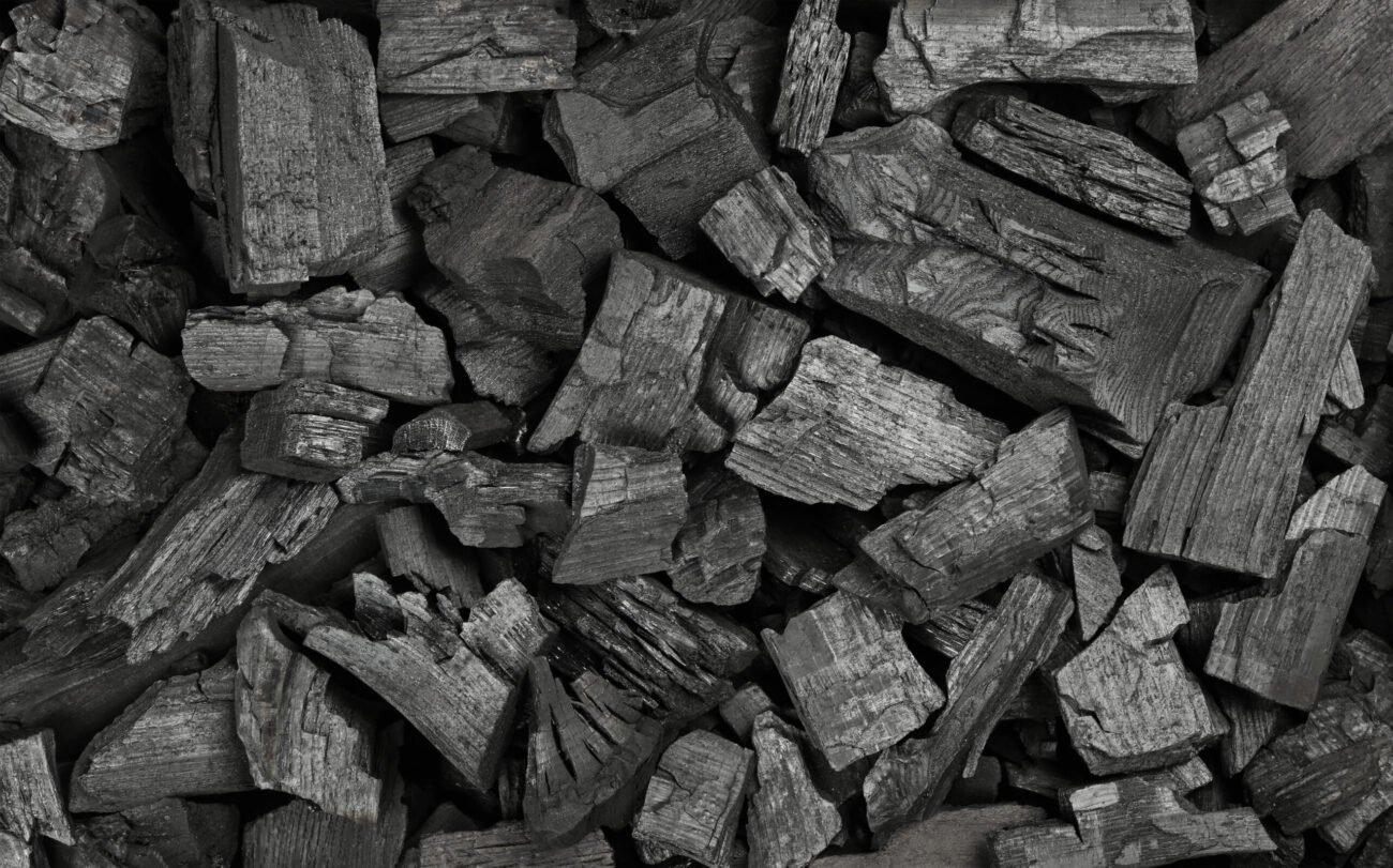 Close up background texture of many black lump charcoal pieces ready for barbecue grill, elevated top view, directly above