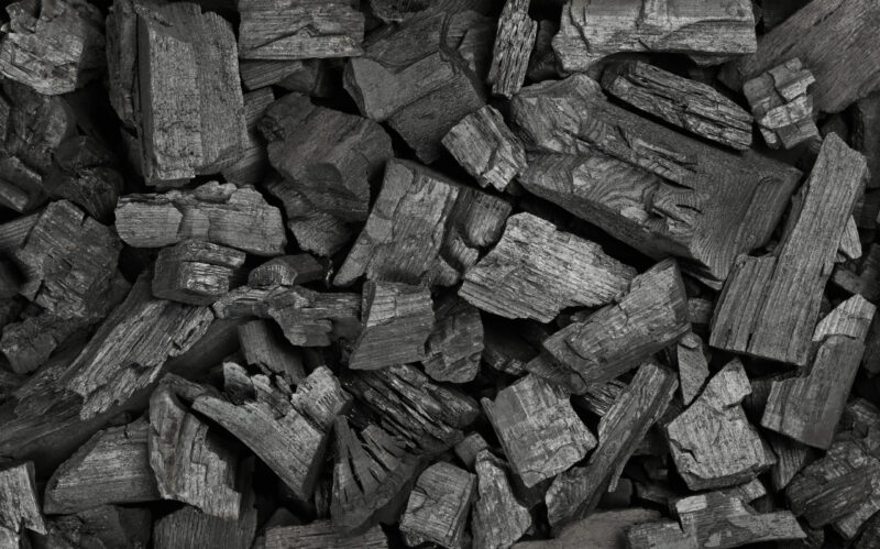 Close up background texture of many black lump charcoal pieces ready for barbecue grill, elevated top view, directly above